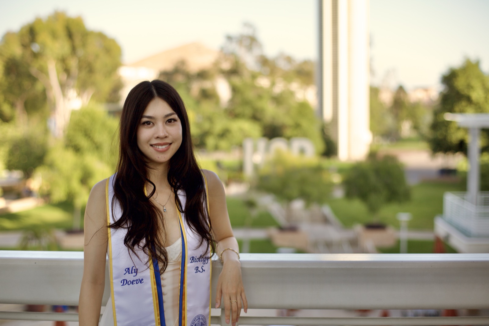 Graduate leaning on railing with campus view