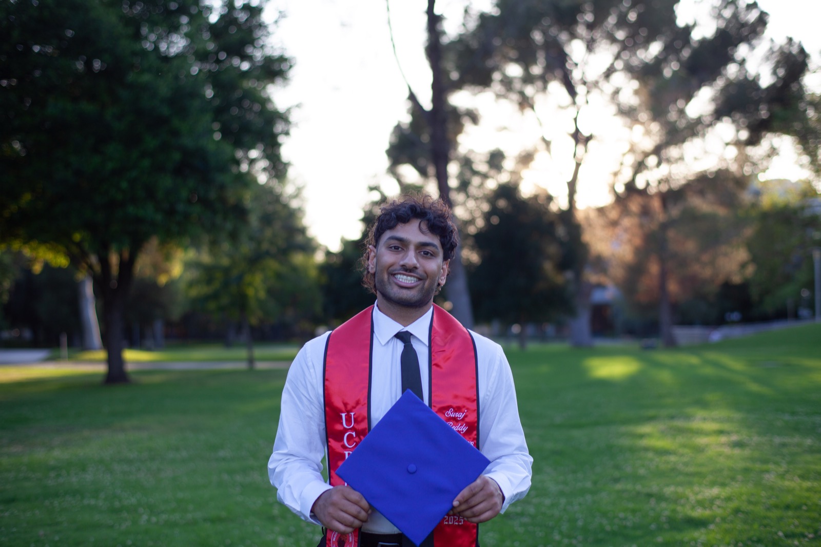 Solo graduate in park at golden hour