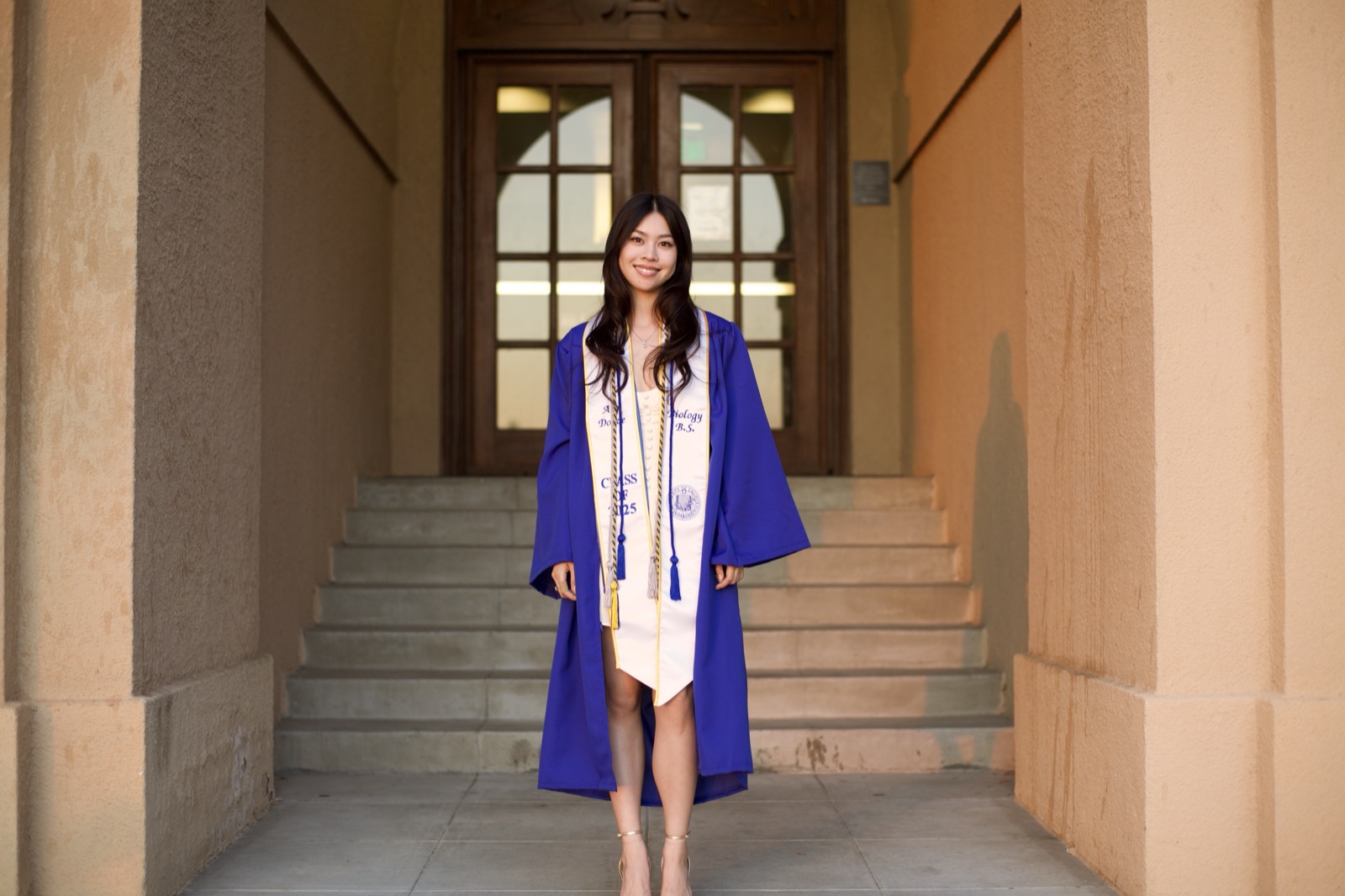 Graduate in blue gown on building steps